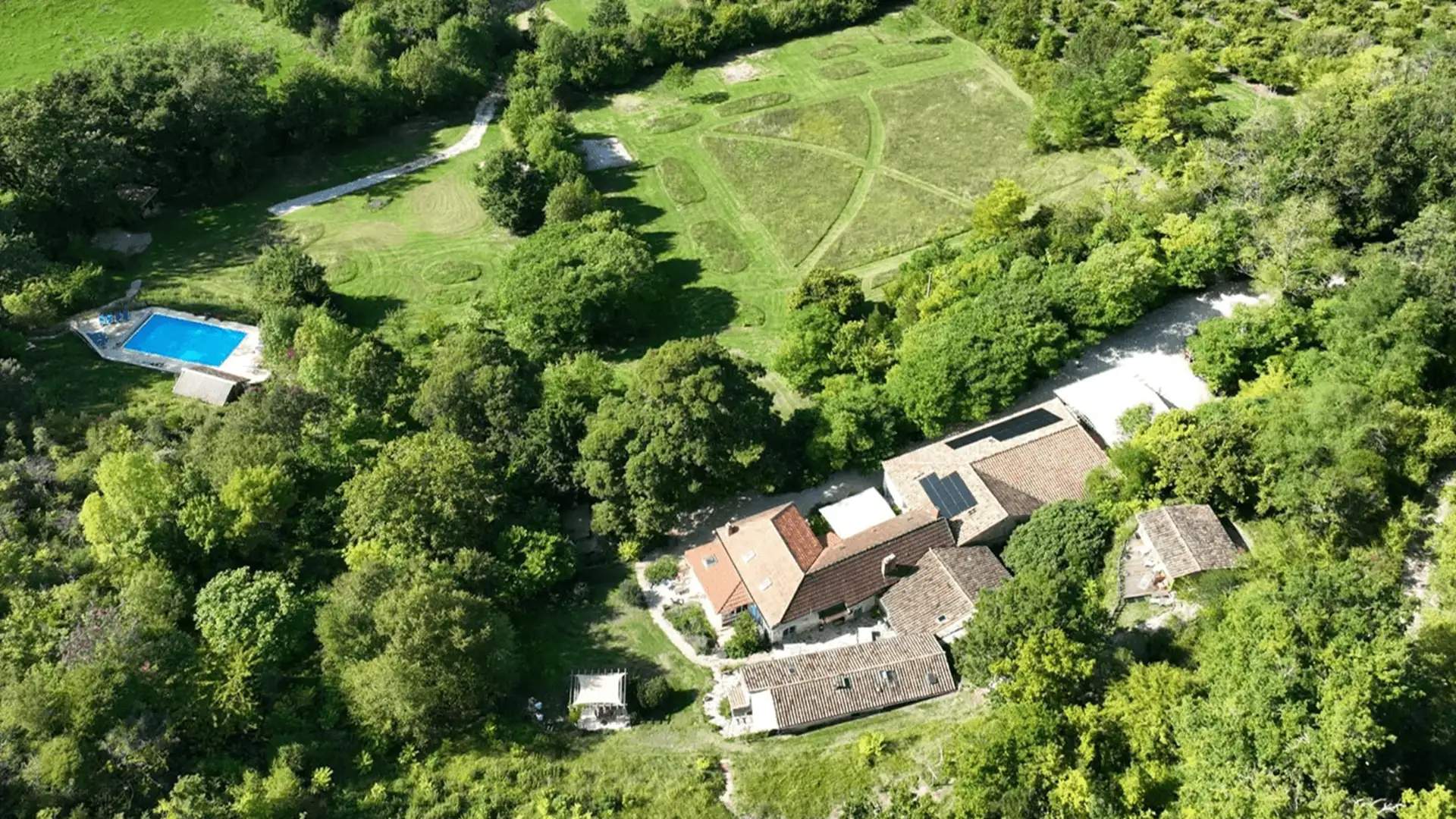 Foto Header Sfeervol uitzicht op het zwembad en de gîtes van Domaine Côte de Fumel in de zon
